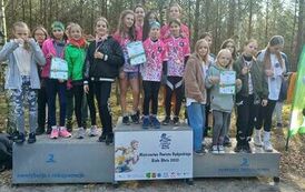 Obraz przedstawia tereny leśne na kt&oacute;rych znajduje się grupa os&oacute;b  stojących na podium