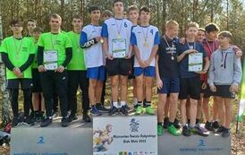 Obraz przedstawia tereny leśne na kt&oacute;rych znajduje się grupa os&oacute;b  stojących na podium