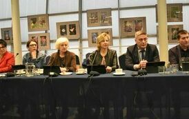 przy stole r&oacute;żnokolorowi ubrani członkowie rady 