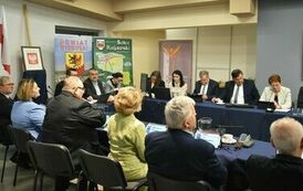 członkowie przy zaręceniu stołu zebrani i dyskutujący razem, część w połowie ucięta na zdjęciu 